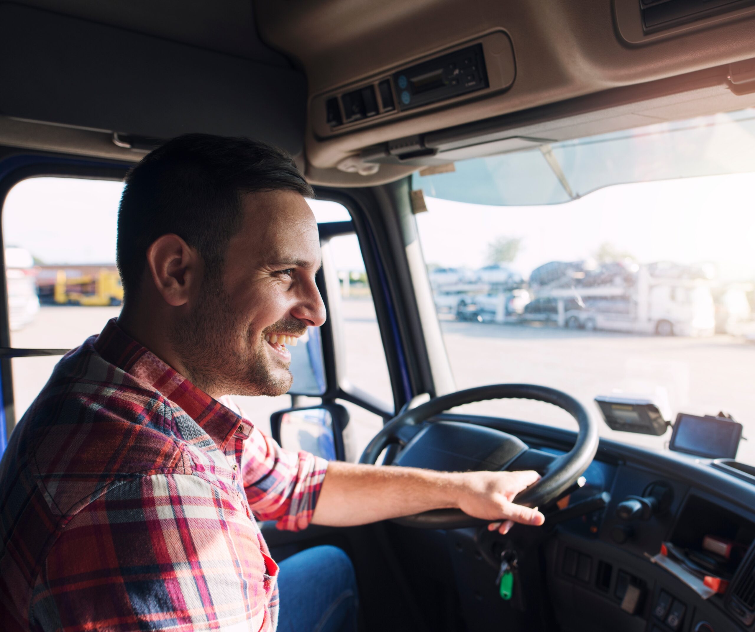 Professional middle aged truck driver in casual clothes driving truck vehicle going for a long transportation route.